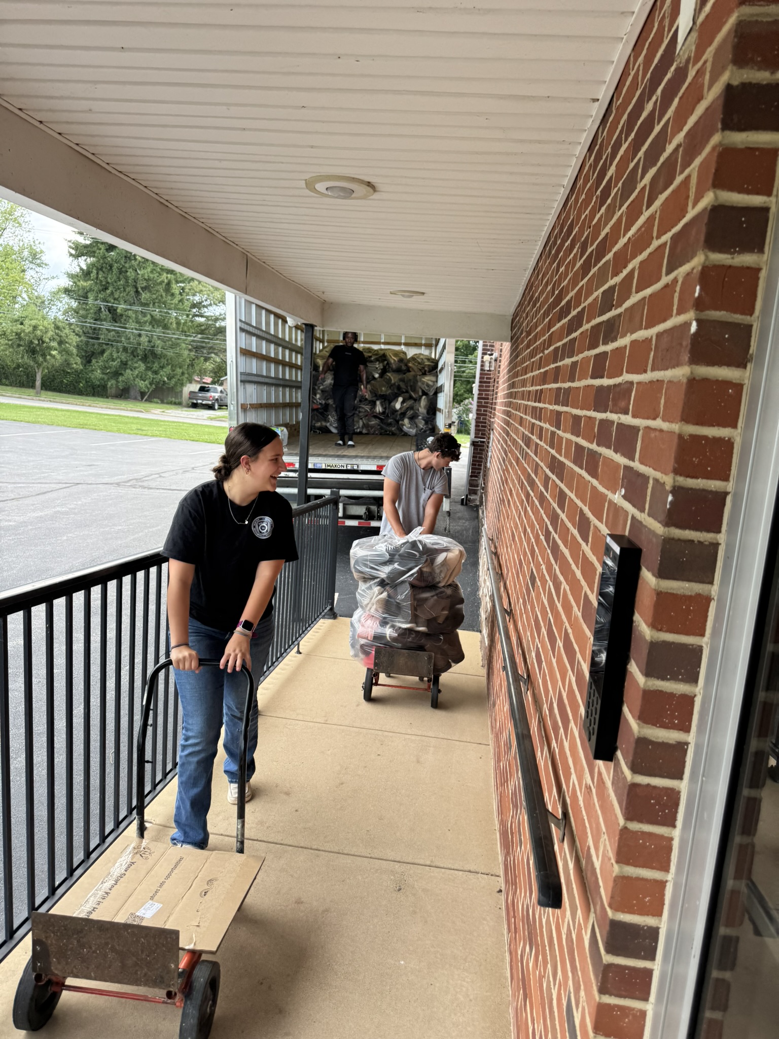 Jordan and Sophia moving shoe bags outside for pickup